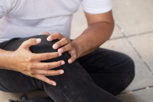 A man sitting on the floor and holding his knee in pain