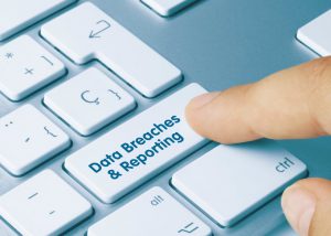 'Data breaches and reporting' written on the enter button on a keyboard. Someone's finger is pressing on the enter button. 