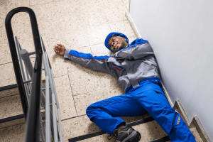 A man lying injured at the bottom of a flight of stairs.